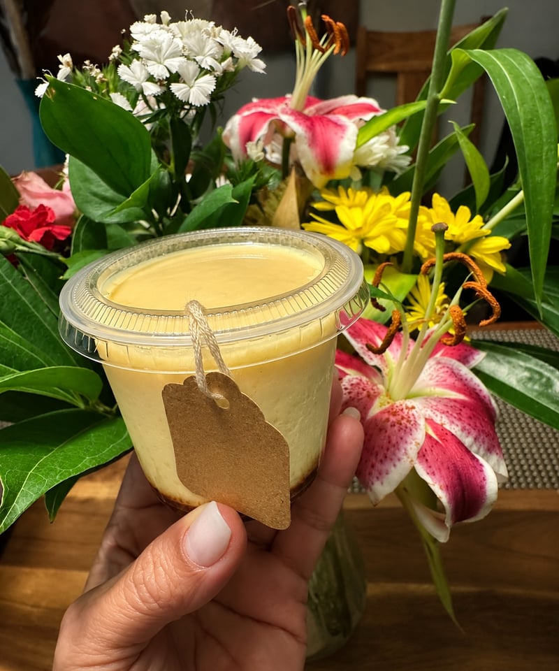 D'Party pudding cup held by hand, surrounded by fresh flowers